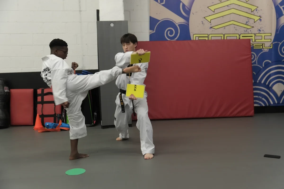 Taekwondo student kicking target held by instructor at Yorkdale Martial Arts